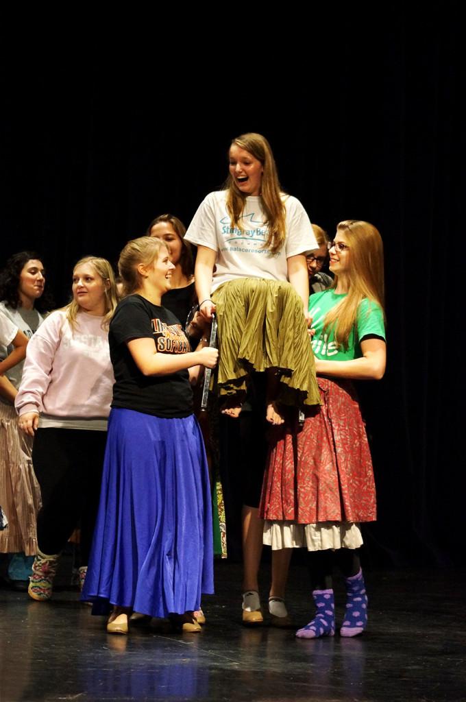 Jane Recker and Cassie Campbell lift Taylor Skie during a scene. 