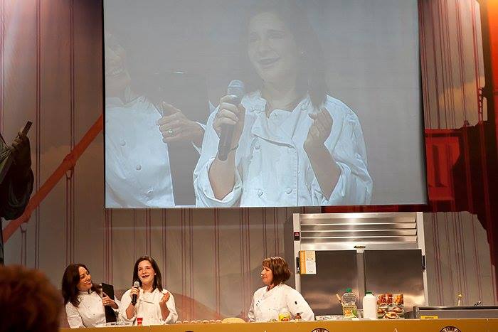 Dawson is shown on a large screen as she performs a cooking demo with Gale Gand.