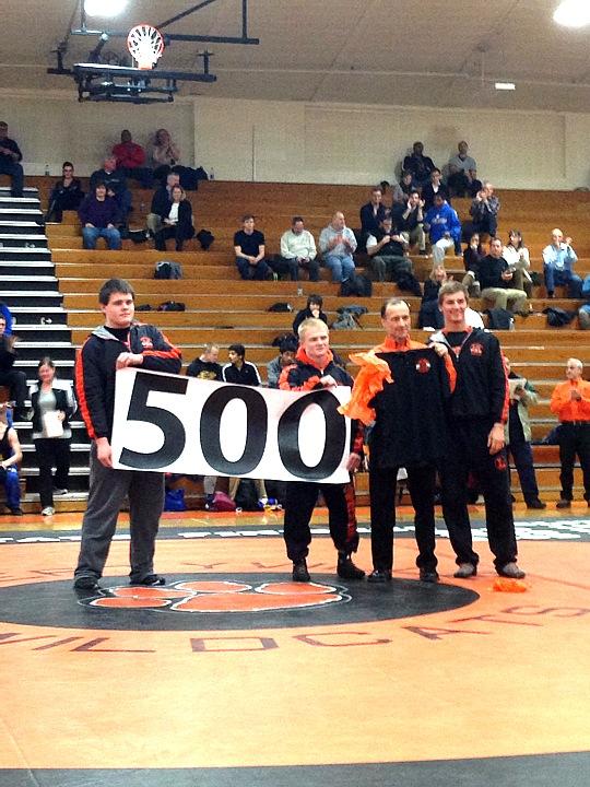 Senior wrestlers Chris McDermand, Stevo Polakowski, and Kayne MacCallum give Mr. Eggert a poster and a T-shirt, congratulating him on his 500 wins.