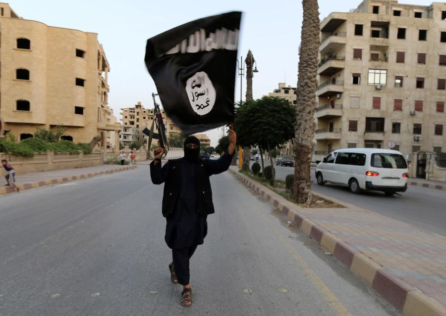 A member of ISIS proudly displays their flag in Syria.