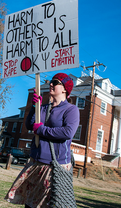 A protester stands outside the University of Virginias Phi Kappa Psi chapter house.
