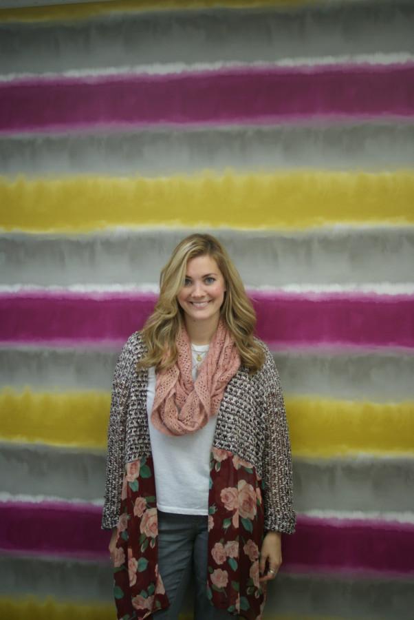 Sarah Potempa smiles while standing in front of her colorful office wall.