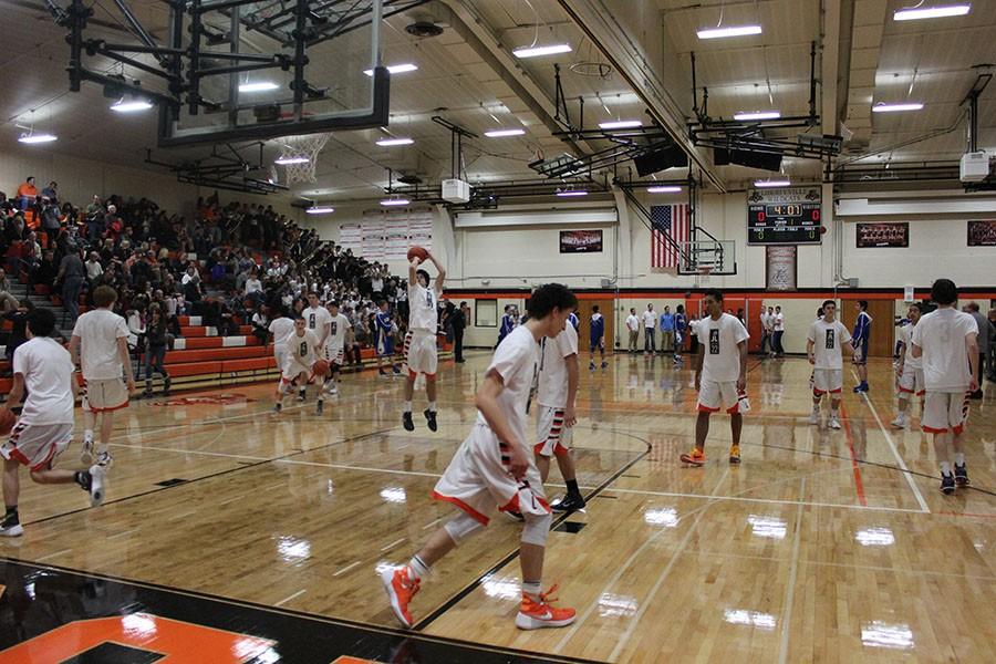 The varsity boys basketball team warms up on the court before facing conference opponent Warren on January 5.