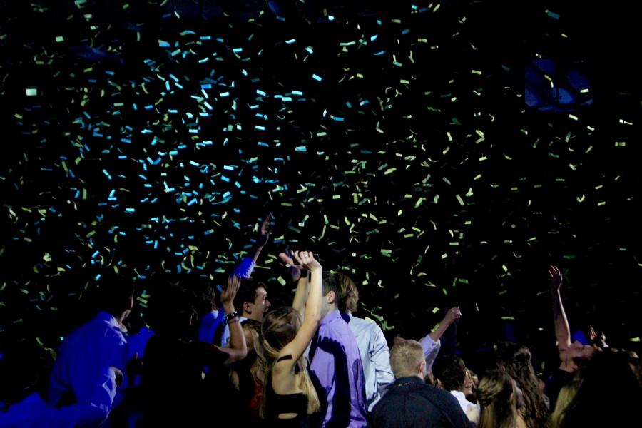 Students dance after the confetti cannon blasts a shower of confetti above them.