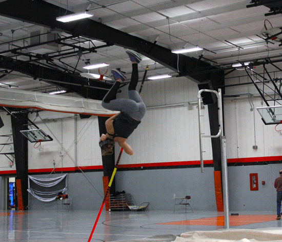 Lily Moore, a senior at LHS, propels her body into the air and over the cross bar as she executes her vault in practice.