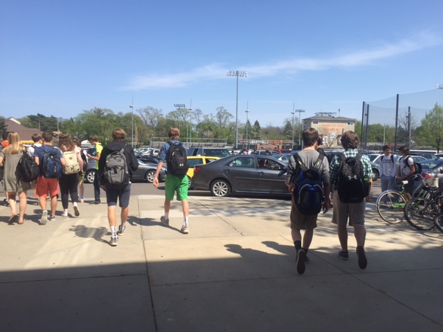 A+mass+amount+of+students+swarm+in+the+parking+lot+after+school%2C+blocking+the+way+for+many+cars.