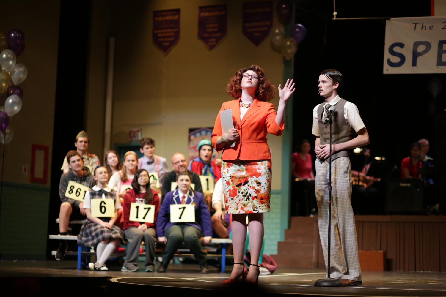 Mia Akers played Rona Peretti, the announcer and alumna of the Spelling Bee. She is seen with John Bleck, playing Douglas Panch, the school principal. 