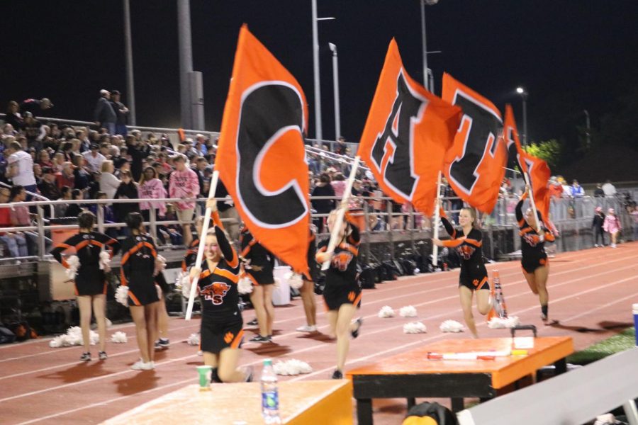 The Libertyville High School varsity cheerleaders run flags that spell out “CATS” up and down the track after every Wildcat touchdown.