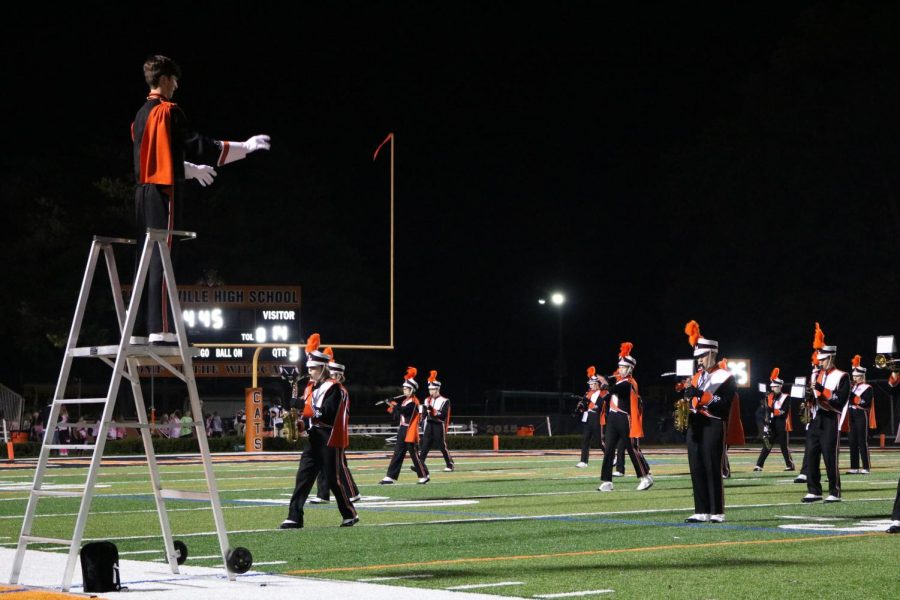 Senior Ian Nagle, a drum major, conducts the marching band during the school’s halftime show. The Marching Wildcats performed the top songs from every ten years starting from 1917.