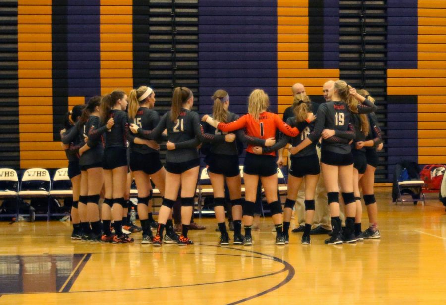 The varsity girls volleyball team huddles during a timeout.