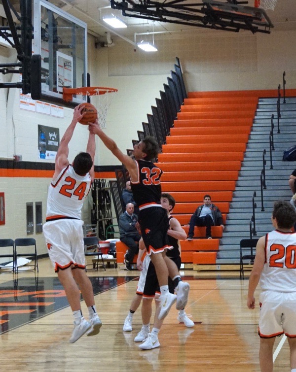 Senior Brendan Cook (24) and junior Travis Clark (32) battle for the rebound after a shot bounced off the backboard.