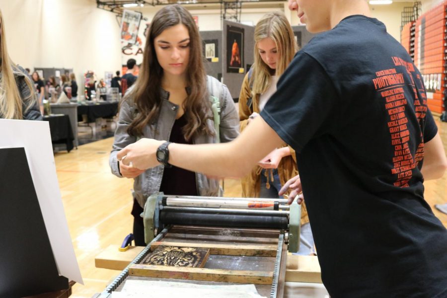 Senior Jackson Czajka shows seniors Julia Picchietti and Mary Cait Rill how to do block printmakings, which is when ink is rolled onto a wooden block, carved with a design and pressed onto a sheet of paper.