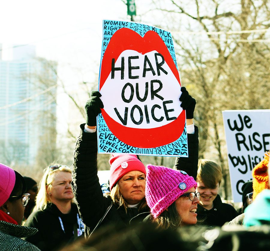 A+woman+holds+up+a+sign+reading+%E2%80%9CHear+our+voice%E2%80%9D+as+she+participates+in+the+Women%E2%80%99s+March+on+Chicago%2C+which+began+at+Columbus+Drive+near+Buckingham+Fountain+and+stretched+all+the+way+to+Randolph+Street%2C+according+to+WTTW.