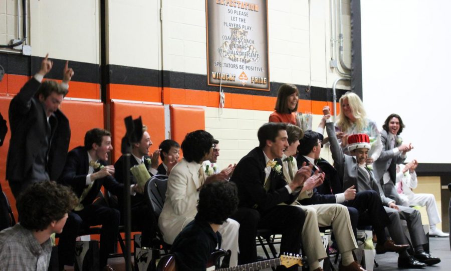 Anton Alesna throws his arm up -- with help from Aaron Chen -- in reaction to being crowned Turnabout King as other court members cheer him on.