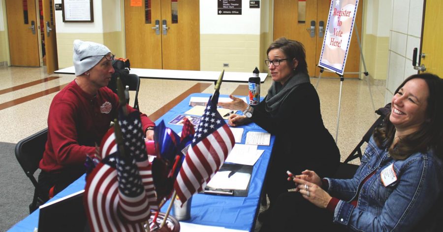 Mr. Scott Schinto, P.E. teacher, fills out his voter registration form while having a laugh with the volunteers.