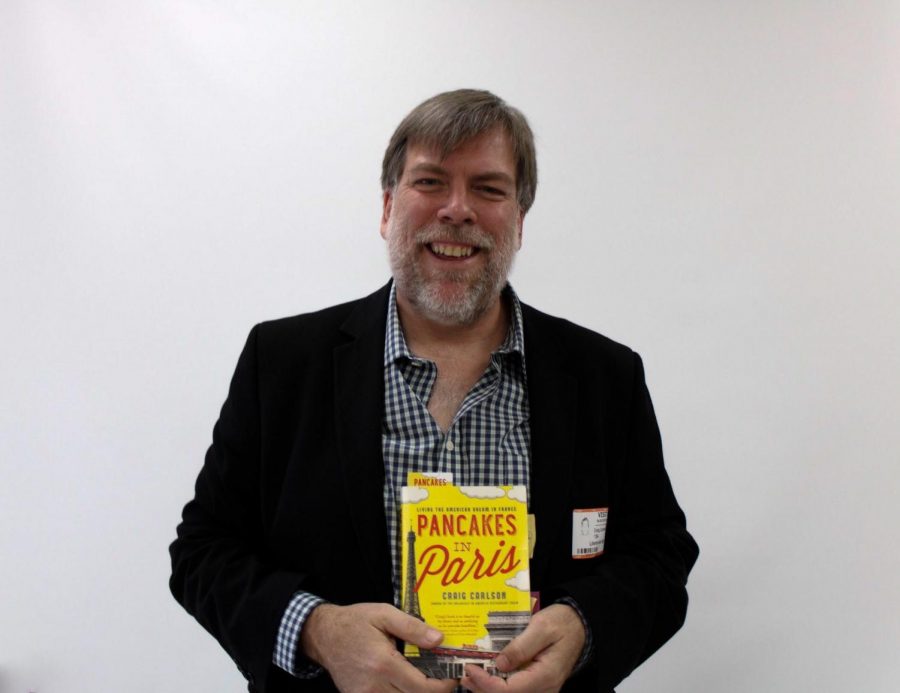 Craig+Carlson+poses+with+his+book%2C+Breakfast+in+America%2C+which+details+the+story+of+how+Mr.+Carlson+came+to+open+his+own+restaurant+in+Paris.