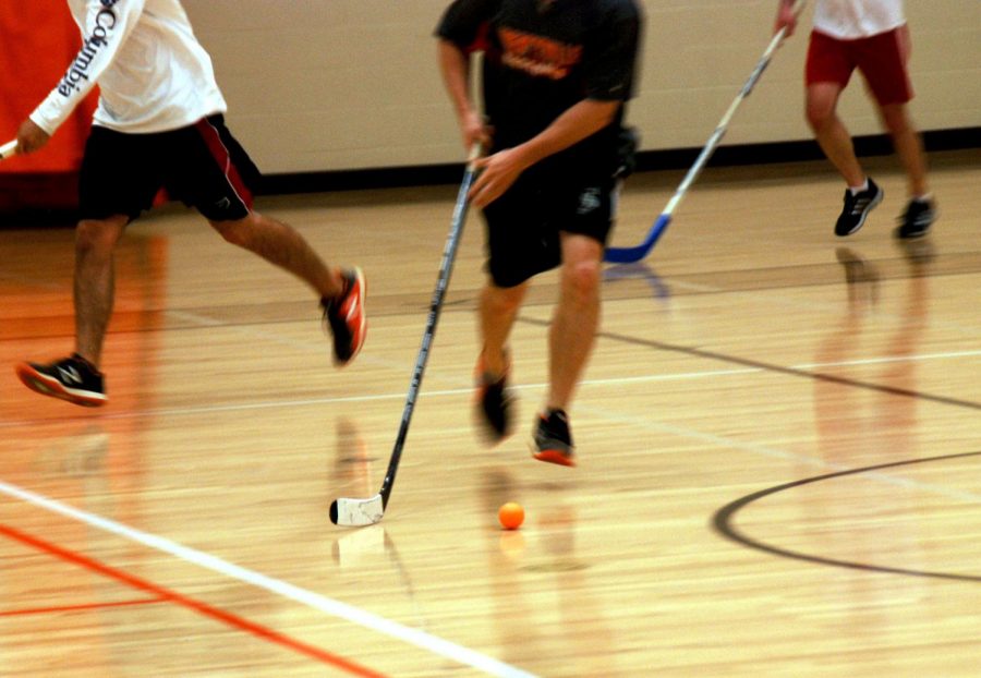 A player on the black team quickly moves the ball down the court towards the white goal. 