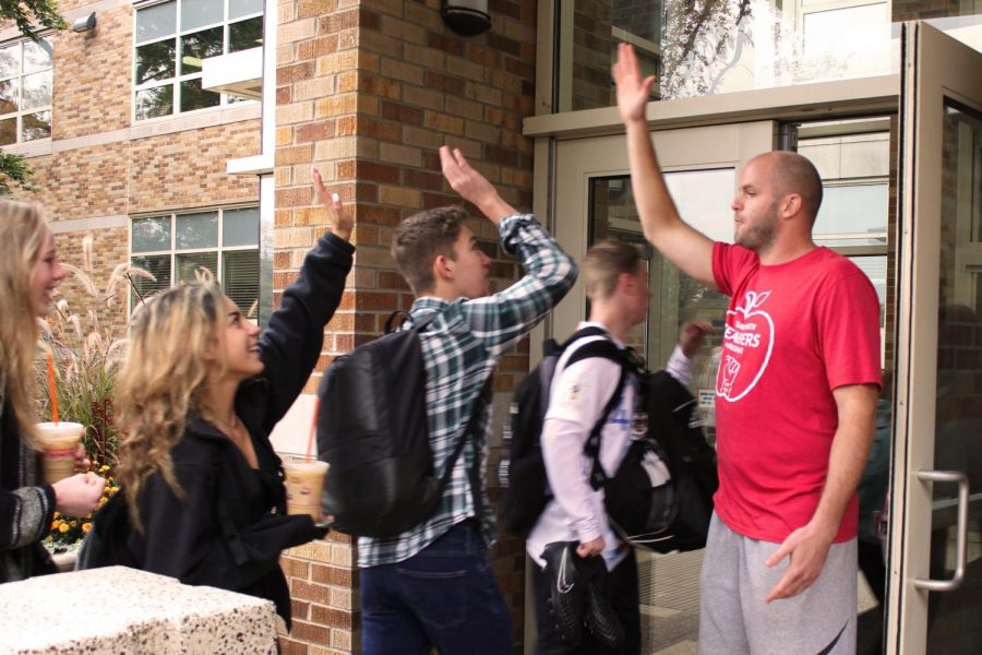 To boost students’ spirits, Mr. Adam Stuart high fives students as they walk into the school on the last day of Red Ribbon Week.