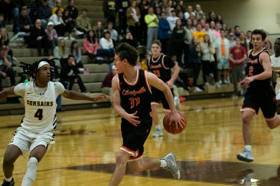 After stripping the ball from his defender, senior captain Josh Steinhaus (11) drives towards the hoop, selflessly tossing Wilterdink (2) a behind-the-back pass to trick the defense.