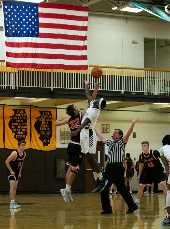 As his teammates follow the ball, senior captain Travis Clark (32) battles for the ball during the tip-off to start the game.