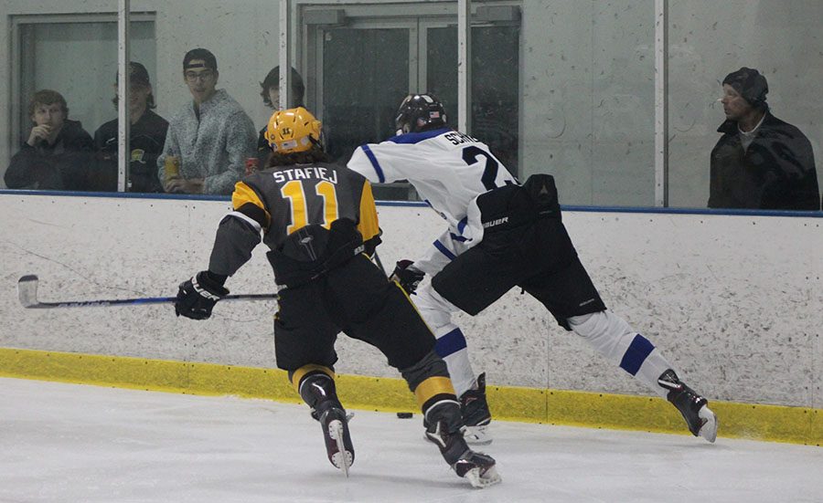 Payton Schweiger battles up the boards against Carmel Junior Zach Stafieji, as spectators watch on. 