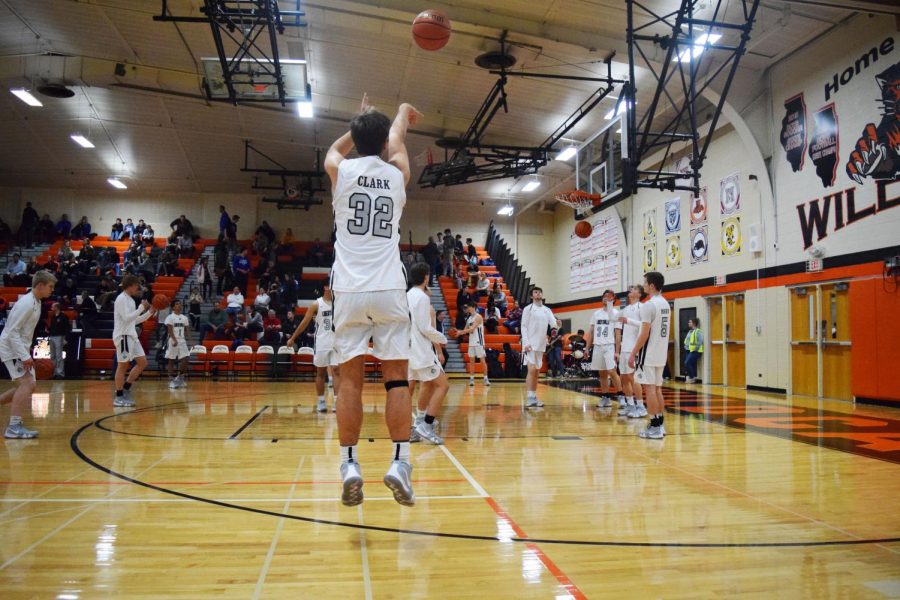 During warmups, senior Travis Clark takes the opportunity to practice his shot from beyond the arc.