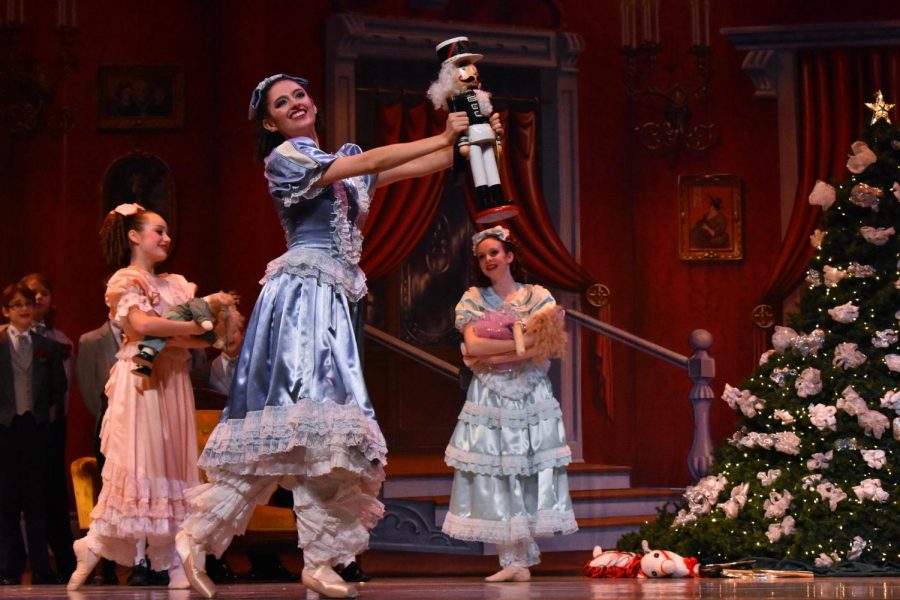 Clara shows off her nutcracker while the other children, danced by the Dance Center North ensemble, admire from afar.