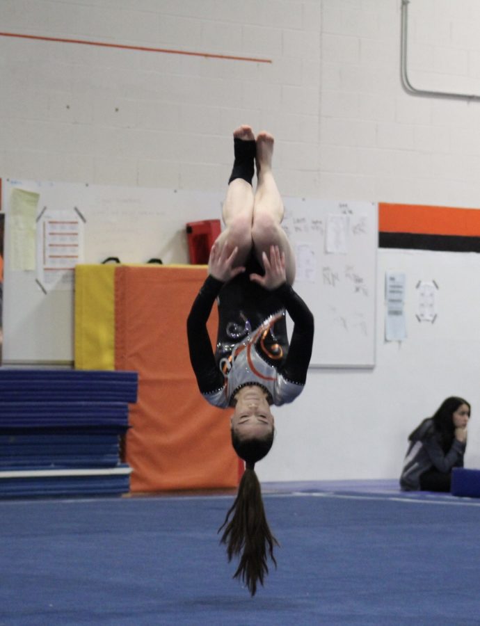 During the middle of her floor routine, Amy Magill completes a back handspring-back handspring-tuck combination, helping her to achieve a final score of 7.15.