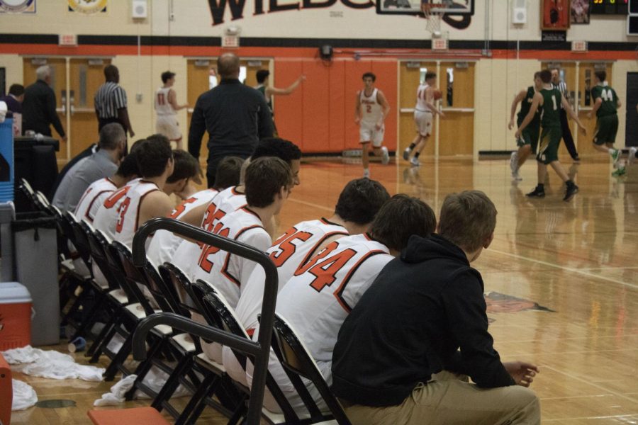 Coaches and players on the bench watch their teammates intently.