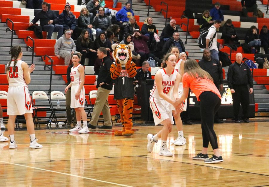 Members of LHS girl's varsity basketball preform a handshake with DOI staff member, and senior Maggie Evers before the game.