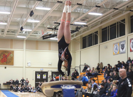 Swanson does a brief handstand on the vault before twisting and landing her jump.