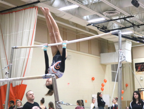 Bertsch competes on the uneven bars. After jumping onto the higher one, she does multiple flips.