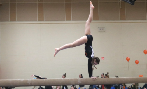 Emaline Frey maintains her balance while performing a front walkover on the beam.