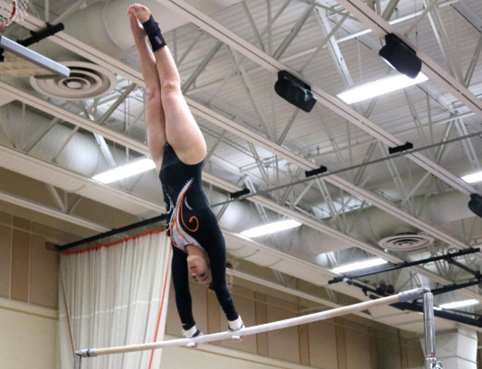 Junior Cameron Hamilton competes on the uneven bars and jumps up to the higher one, where she holds a brief handstand.