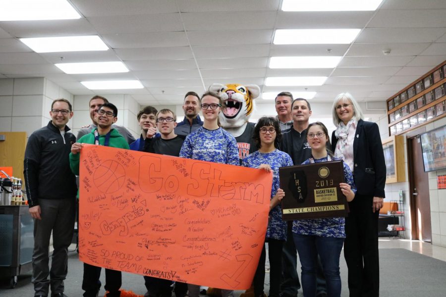 Team Storm poses with some of their coaches and LHS staff. They hold a banner that their classmates and friends at the Wildcat Warehouse made them in support of the team’s victory at state. 
