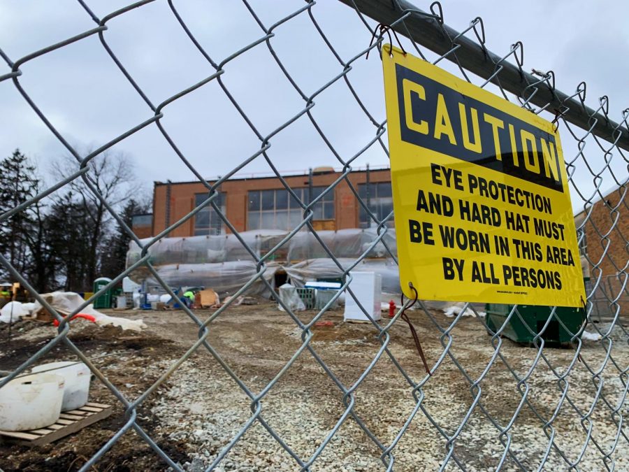 The area where the pool is being built and around where it is being built is fenced in, with much of the fenced in area filled by construction equipment and machinery. 