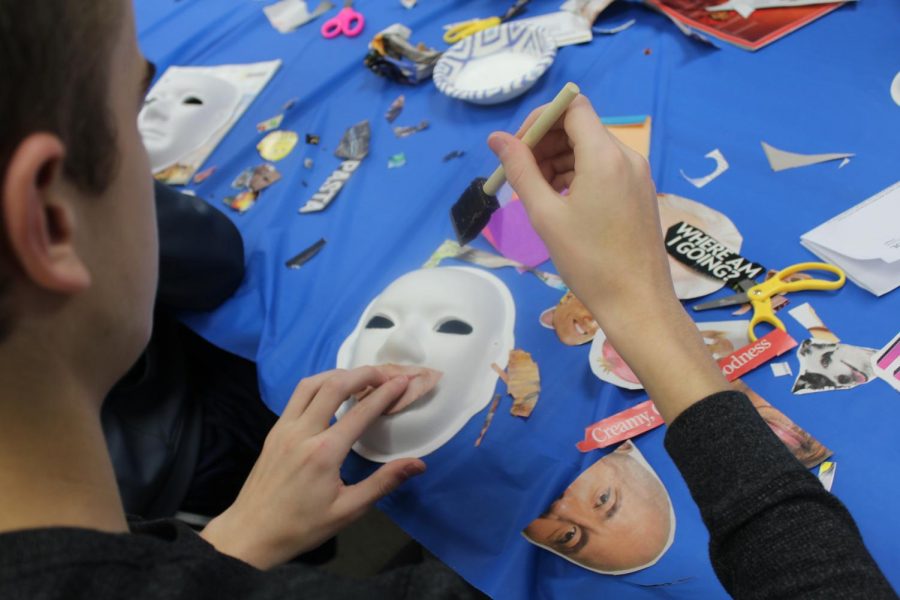 A student participates in creating a mask to represent themselves through images and words. 