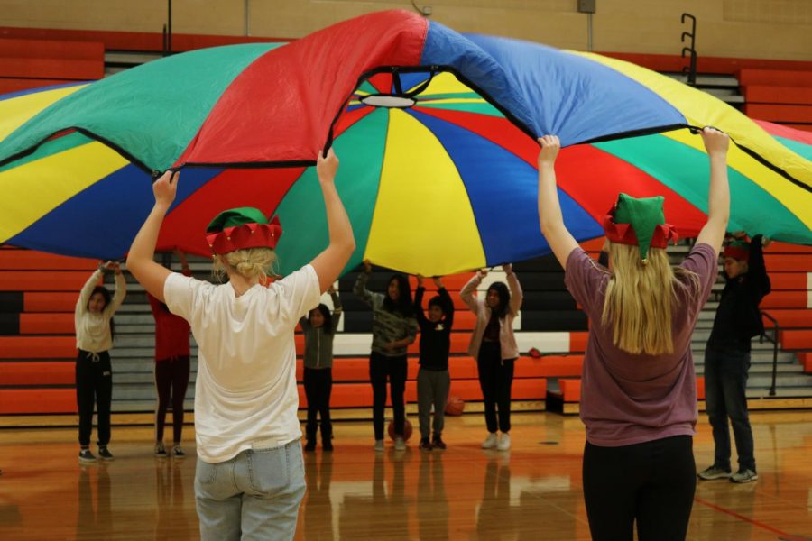 Student volunteers and kids attending the event have fun playing with the parachute in the main gym.