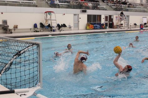 Regan shoots while the goalie reaches up to try and match his movements.