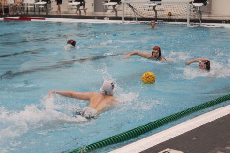 Two Libertyville players speed towards the ball trying to prevent the Maine East player from reaching it first.