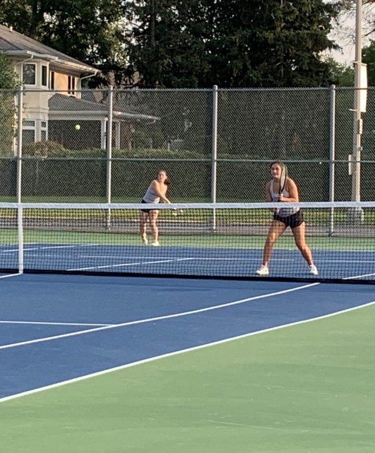 Senior Jenna Zaengle (left) follows through on a shot while her partner, junior Michaela Orvis, prepares for their opponent to hit a return shot.