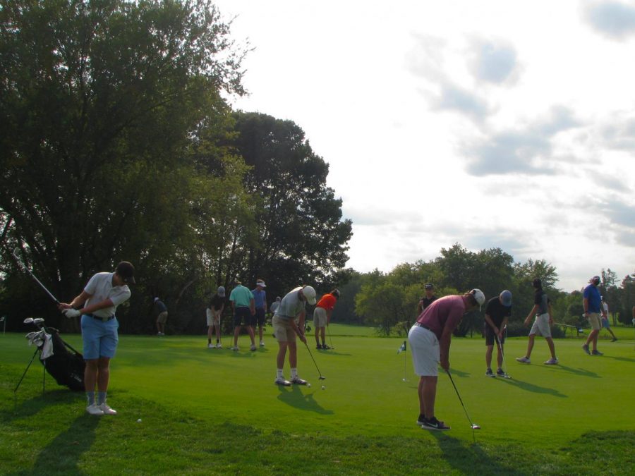 The varsity boys golf team practices putting while six feet apart at Pine Meadow, their home golf course.