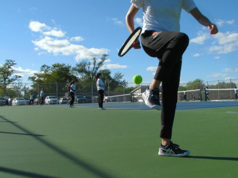 In order to follow COVID-19 guidelines, members of the girls tennis team must pick up balls during practice by capturing the ball in between their foot and their racquet, lifting their leg to bounce the ball, and finally catching the ball with their racquet.