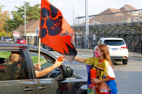 Senior Jane Arnold, wearing a can costume to promote the canned food drive, hands off a Student Council souvenir at the Homecoming drive-through parade.