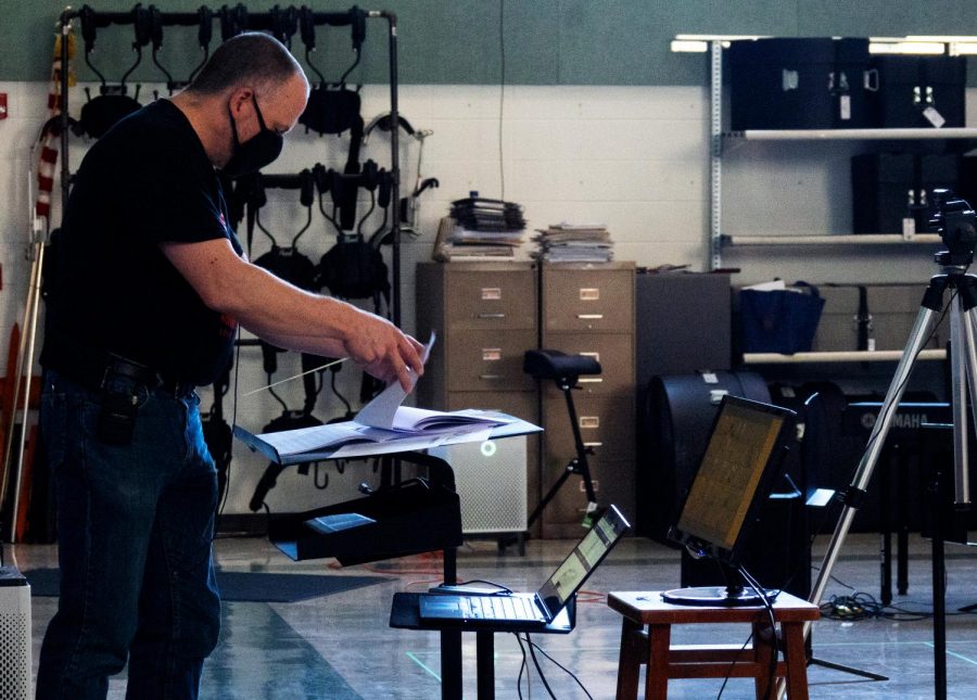 Fine arts classes aim to connect their in-person and at-home groups by allowing online students to follow along with the in-person rehearsal. Band director Adam Gohr achieves this by setting up a monitor and microphone so that online band students can follow his conducting.