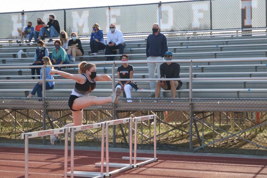 Senior+Katie+Stone+leaps+into+action+over+the+hurdles+as+she+warms+up+for+her+race.