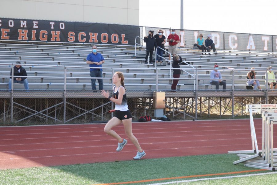 Junior varsity team member Payton Grana finishes the second of her two laps around the track in the longest relay to the cheers of her teammates.