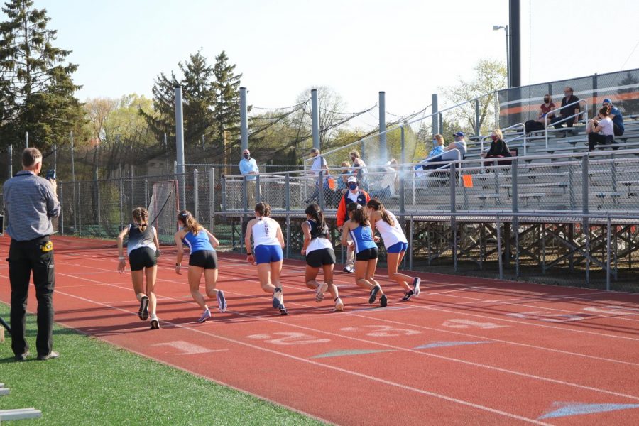 Two runners from each team compete in the 100 meter dash as the starter pistol goes off to signify the beginning of the race.