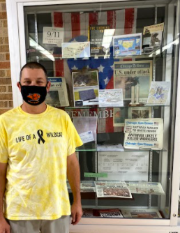 Mr. O’Neill stands beside his display case showcasing artifacts from the months preceding the 9/11 attack. The display case included: newspapers, books, diagrams, and the American flag.