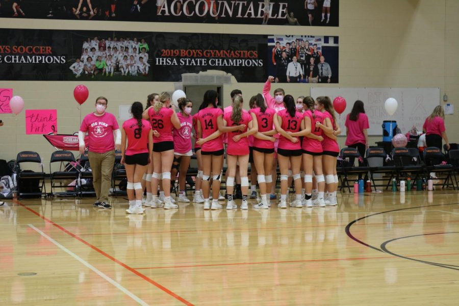 The team gathers in a huddle at halftime after winning the first set over Vernon Hills.